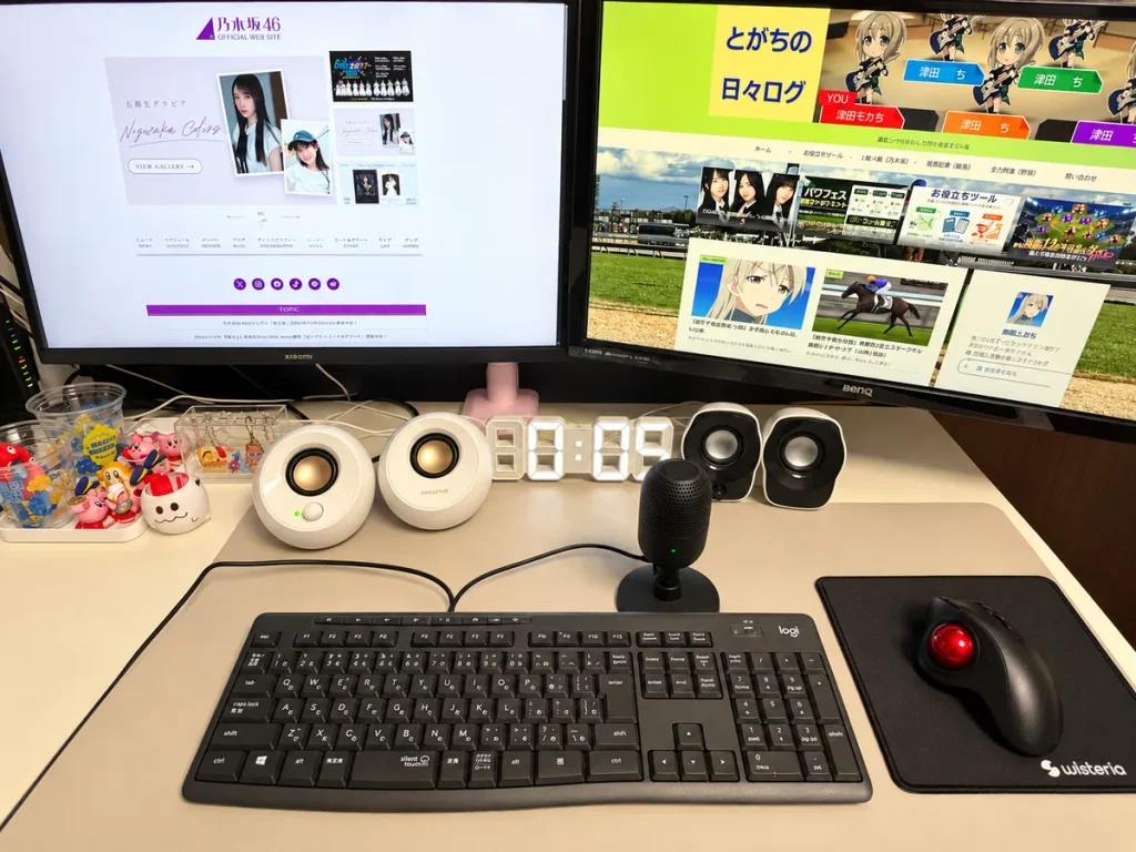 Xiaomi A27Qi 2026（左）とBenQモニター（右）をモニターアームで設置したデュアルモニター環境。デスクにはCreative PebbleのスピーカーやRazerのマイクも配置。